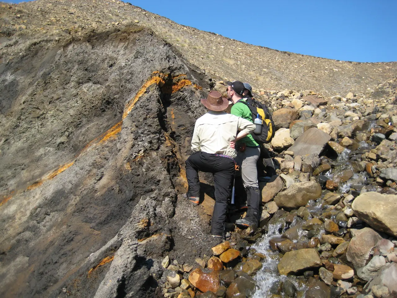 Field team sampling a rock outcrop